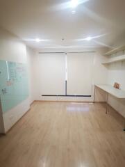 Empty room with wooden floor, whiteboard, shelves and a desk