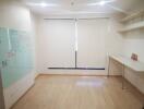 Empty room with wooden floor, whiteboard, shelves and a desk