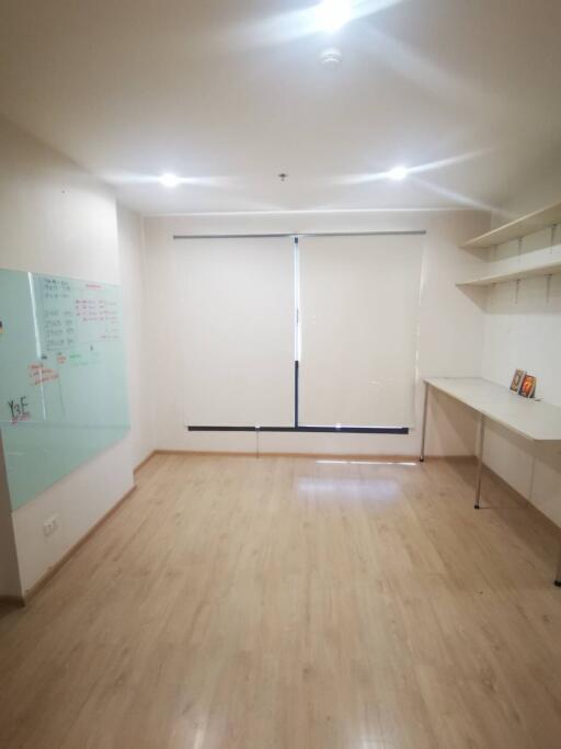 Empty room with wooden floor, whiteboard, shelves and a desk