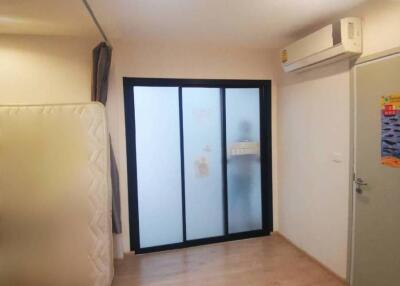 Empty bedroom with frosted glass sliding door and air conditioner.