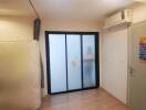 Empty bedroom with frosted glass sliding door and air conditioner.