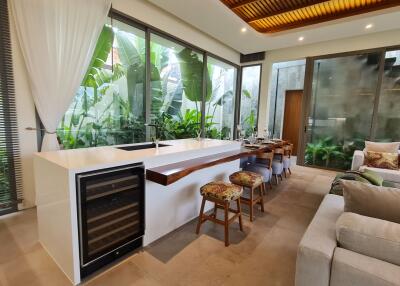 Modern kitchen with large windows, breakfast bar, and adjacent living area.