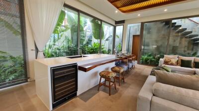 Modern kitchen with large windows, breakfast bar, and adjacent living area.