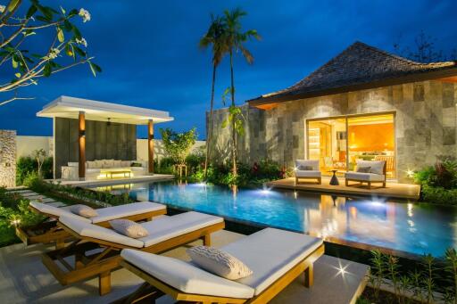 Outdoor area with pool, lounge chairs, and a house at dusk