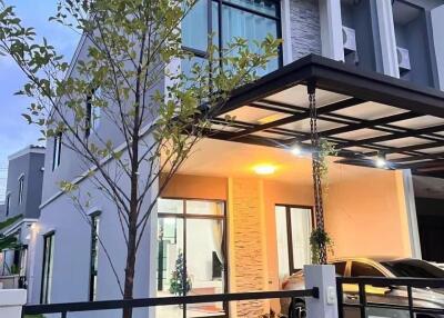 Modern two-story house with carport and tree in front yard