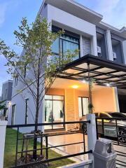 Modern two-story house with carport and tree in front yard