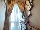 Elegant staircase with chandelier and large window