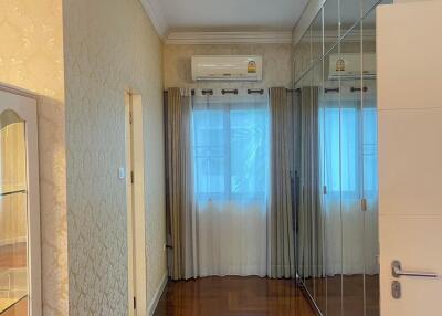 A polished wooden floor hallway with large mirrored wardrobes and a window with modern curtains