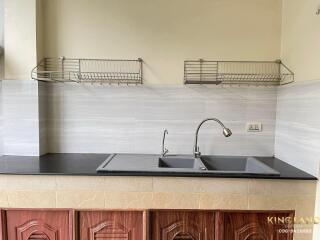 A kitchen sink with countertop and wall-mounted racks