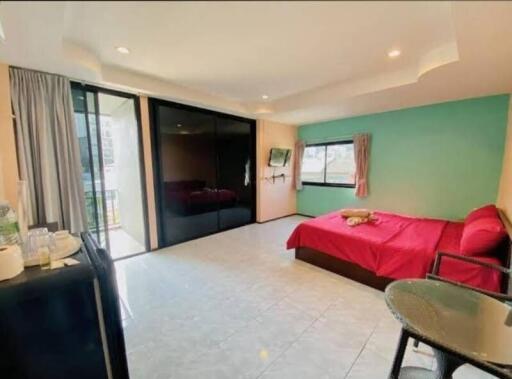 Spacious bedroom with large window, bed, wardrobe and a small dining area