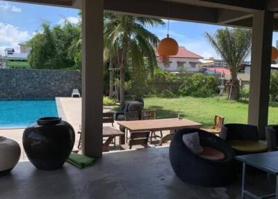 Covered outdoor patio with view of pool and garden