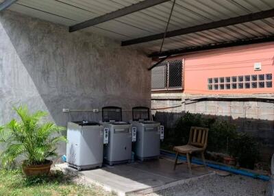 Outdoor covered area with washing machines and a chair