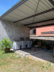 Outdoor covered area with washing machines and a chair