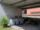 Outdoor covered area with washing machines and a chair