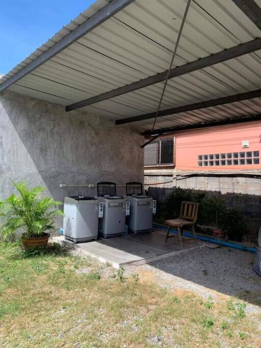 Outdoor covered area with washing machines and a chair