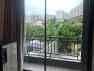 Living room with sliding glass door leading to a balcony with a view of other buildings and greenery