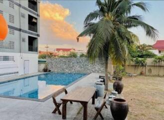 Outdoor pool area with a table, chairs, and palm tree