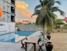 Outdoor pool area with a table, chairs, and palm tree