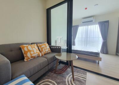 Living room with sofa, table, and a view into the bedroom