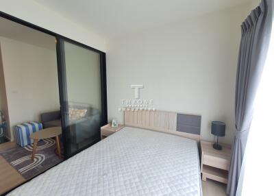 Bedroom with bed, bedside table, lamp, and glass sliding door to living area