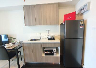 Modern kitchen with wooden cabinets, countertop, sink, stove, microwave, and refrigerator