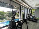 Modern gym with exercise equipment and pool view