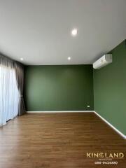 Spacious living room with wooden flooring and green accent wall