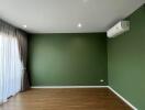 Spacious living room with wooden flooring and green accent wall