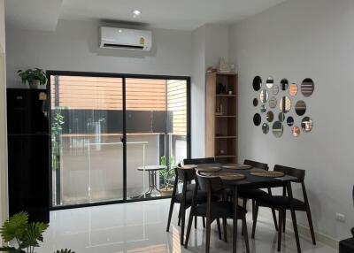 Modern dining area with large sliding glass doors, mirror wall decor, and indoor plants