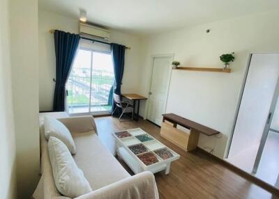 Modern living room with sofa, coffee table, desk, and large window with curtains