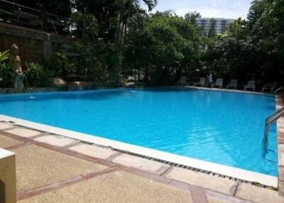 Outdoor pool area with clear blue water and surrounding greenery