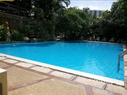 Outdoor pool area with clear blue water and surrounding greenery