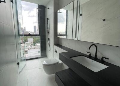 Modern bathroom with white tiles, glass shower, and black fixtures