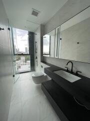 Modern bathroom with white tiles, glass shower, and black fixtures