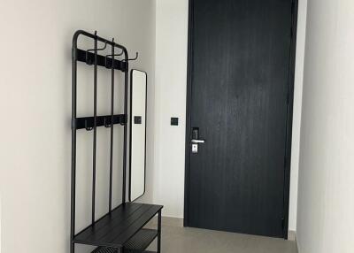 Modern apartment entryway with coat rack and dark door