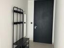 Modern apartment entryway with coat rack and dark door