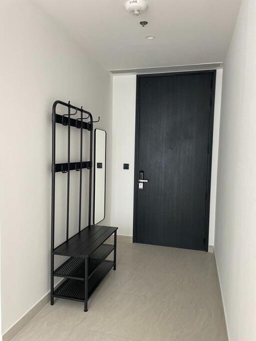 Modern apartment entryway with coat rack and dark door