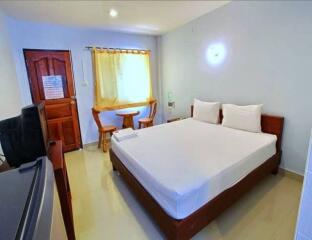 Well-lit bedroom with a double bed, wooden furniture, and window