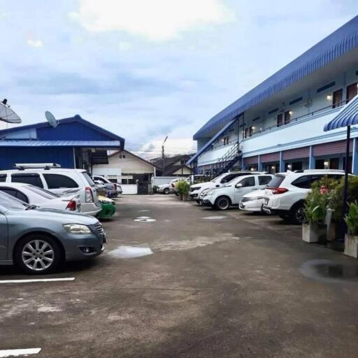 Parking area in front of a multi-story building with blue roofs