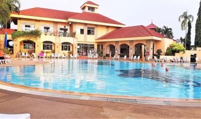 Outdoor swimming pool with surrounding lounge chairs and a large building in the background