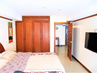 Bedroom with a bed, closet, wall-mounted TV, and open door