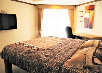 Bedroom with modern decor, wall-mounted TV, and workdesk