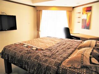 Bedroom with modern decor, wall-mounted TV, and workdesk