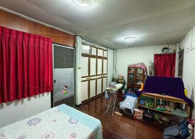 Bedroom with red curtains and a variety of stored items