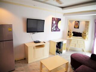 Modern living area with desk, TV, and fridge