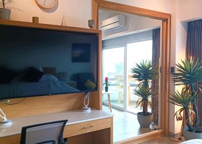 Modern bedroom with large TV, desk, and balcony access