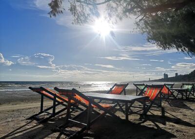 Beachfront view with lounge chairs and tables