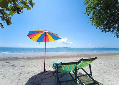 Colorful umbrella and chairs on a sandy beach with clear blue waters