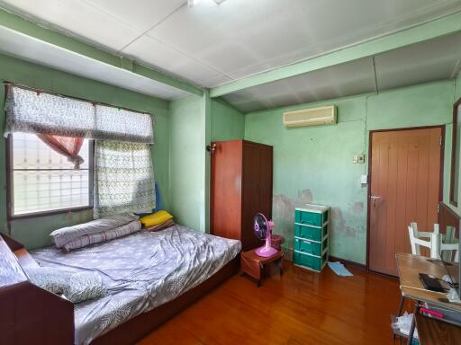 A modest bedroom with basic furniture and air conditioning