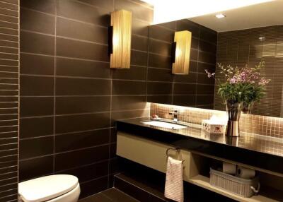 Modern bathroom with dark tiles, floating sink, and decorative lighting